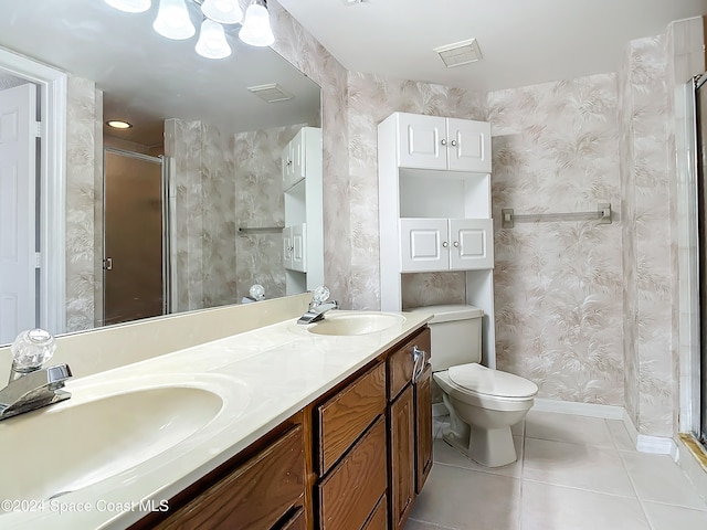 bathroom with tile patterned floors, a shower with door, vanity, and toilet