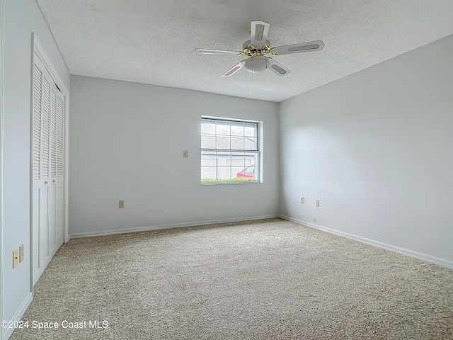 unfurnished bedroom with ceiling fan, a closet, light colored carpet, and a textured ceiling