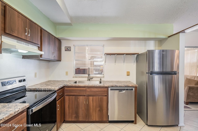 kitchen featuring sink, light stone countertops, a textured ceiling, light tile patterned floors, and stainless steel appliances