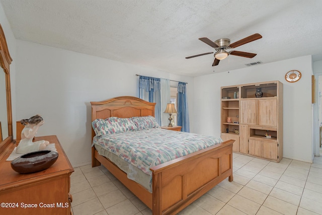 bedroom featuring ceiling fan, light tile patterned flooring, and a textured ceiling