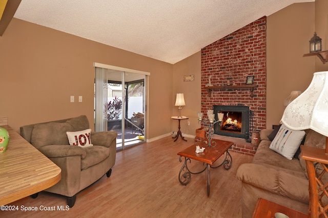 living room featuring a brick fireplace, a textured ceiling, hardwood / wood-style flooring, and vaulted ceiling