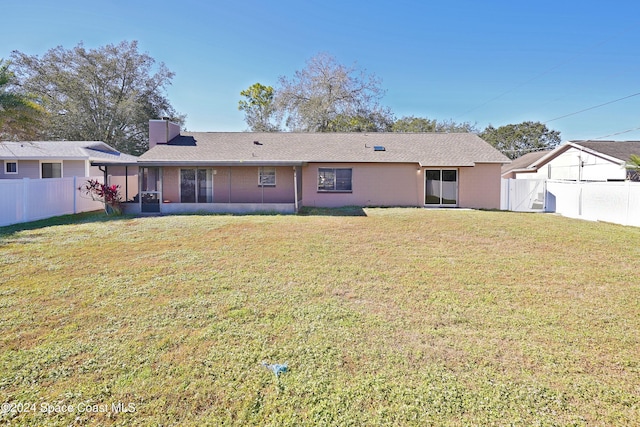 rear view of property with a sunroom and a yard