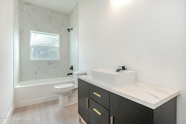 full bathroom with hardwood / wood-style floors, vanity, tiled shower / bath combo, and toilet