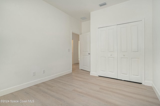 unfurnished bedroom with light wood-type flooring and a closet