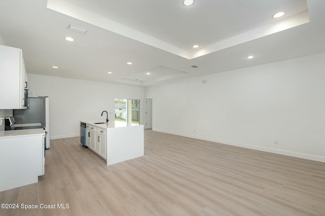 kitchen featuring white cabinets, light hardwood / wood-style floors, sink, and a tray ceiling