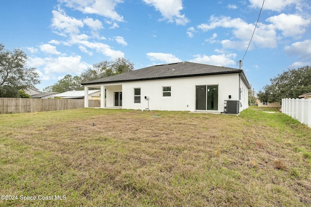 rear view of property featuring cooling unit and a yard