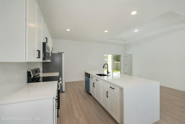 kitchen featuring stainless steel appliances, sink, light hardwood / wood-style flooring, white cabinets, and an island with sink