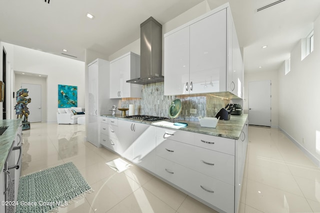 kitchen with white cabinetry, wall chimney range hood, stainless steel gas cooktop, and tasteful backsplash