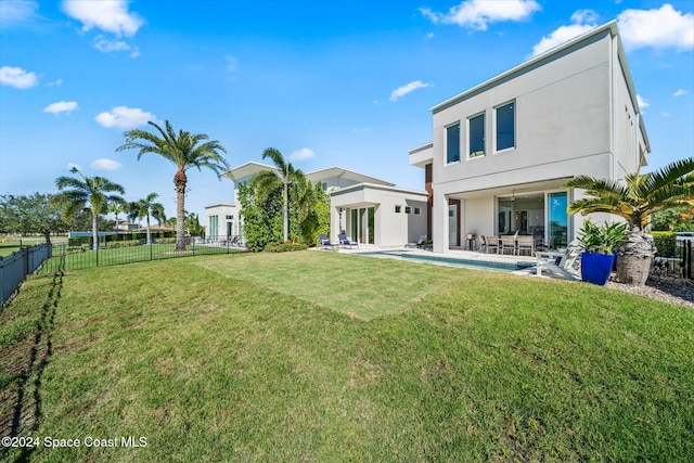 back of property with a lawn, a patio area, and a fenced in pool