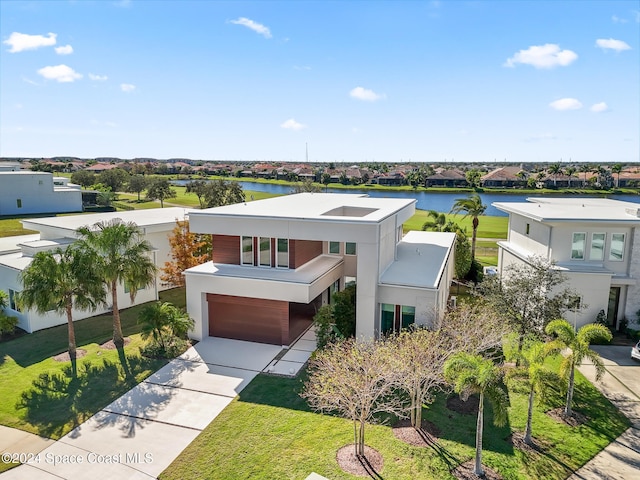 view of front of home featuring a front lawn, a water view, and a garage