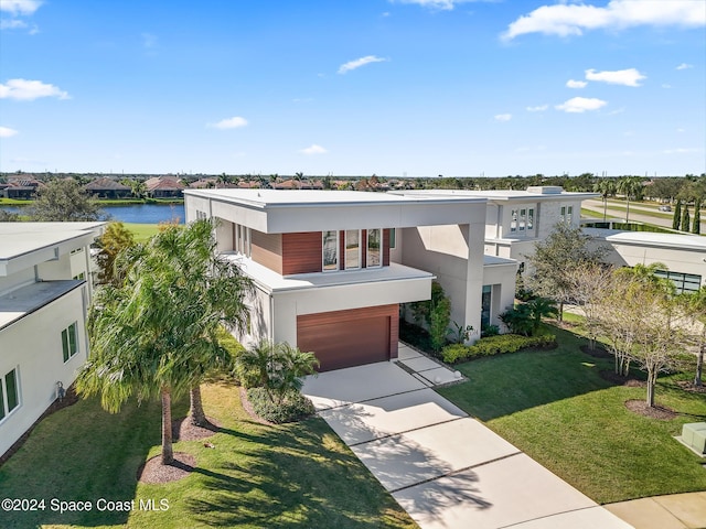 contemporary house featuring a water view, a front yard, and a garage