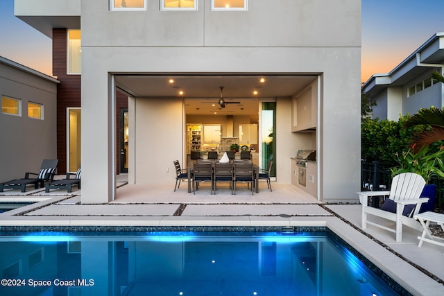 pool at dusk featuring a patio, area for grilling, and ceiling fan