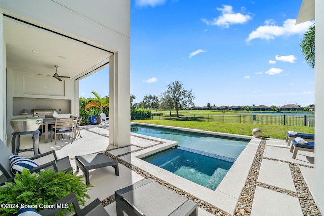 view of swimming pool featuring a lawn, ceiling fan, and a patio