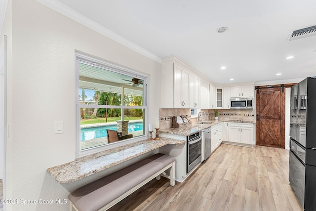 kitchen featuring appliances with stainless steel finishes, tasteful backsplash, sink, a barn door, and white cabinets