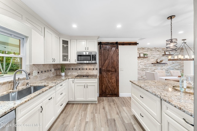 kitchen featuring appliances with stainless steel finishes, sink, a barn door, light hardwood / wood-style flooring, and white cabinets