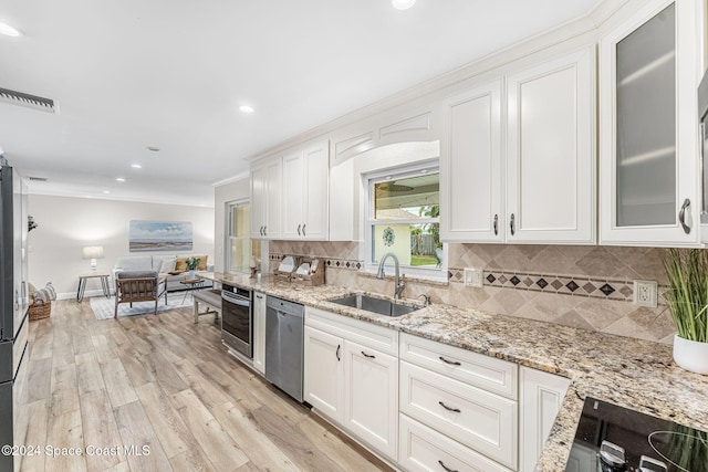 kitchen with sink, white cabinets, light hardwood / wood-style flooring, and appliances with stainless steel finishes