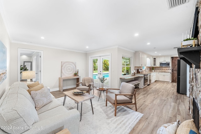 living room with light hardwood / wood-style floors, ornamental molding, wine cooler, and french doors