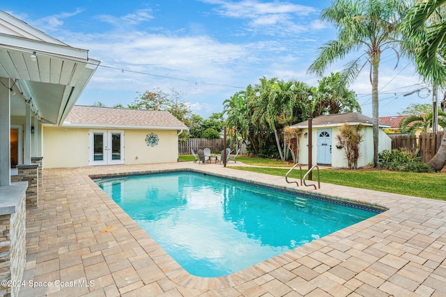 view of swimming pool with a patio area, french doors, and an outdoor structure