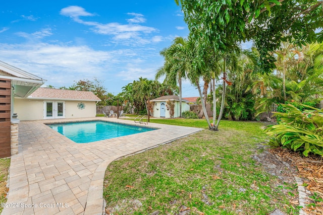 view of swimming pool with a lawn, a storage unit, a patio area, and french doors