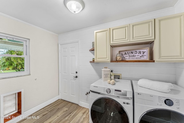 clothes washing area featuring ornamental molding, washer and clothes dryer, cabinets, and light hardwood / wood-style floors