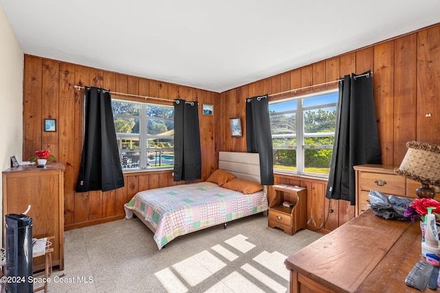 bedroom with multiple windows and wood walls