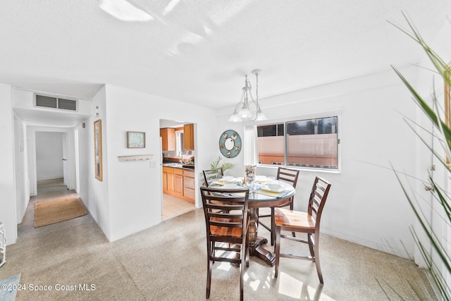 dining area featuring light carpet, a textured ceiling, and a chandelier