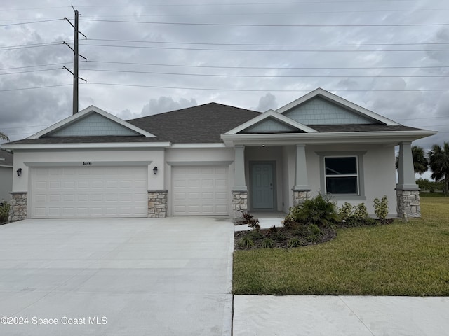 view of front of property with a porch, a garage, and a front lawn