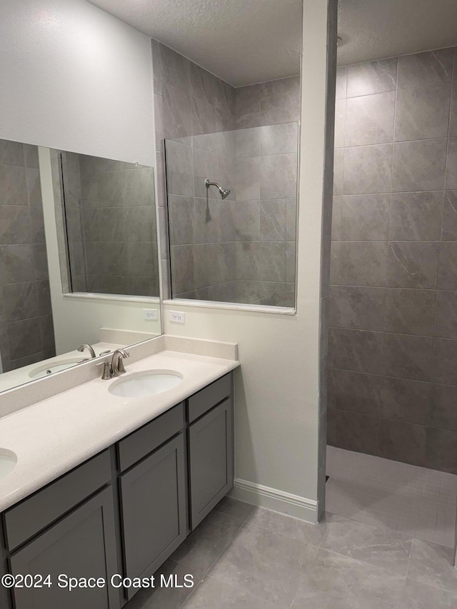 bathroom with vanity, a tile shower, and a textured ceiling