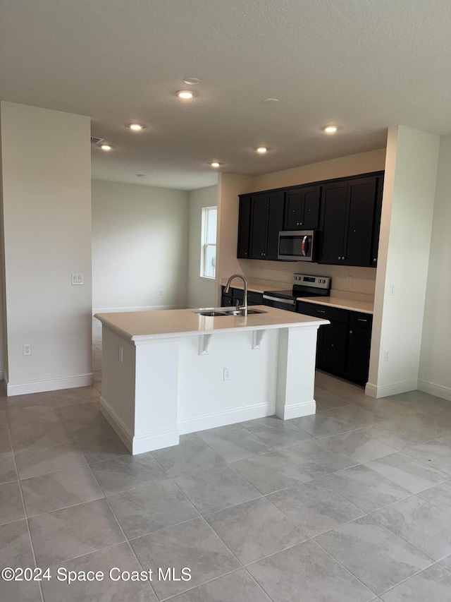 kitchen featuring sink, a kitchen bar, a kitchen island with sink, and stainless steel appliances