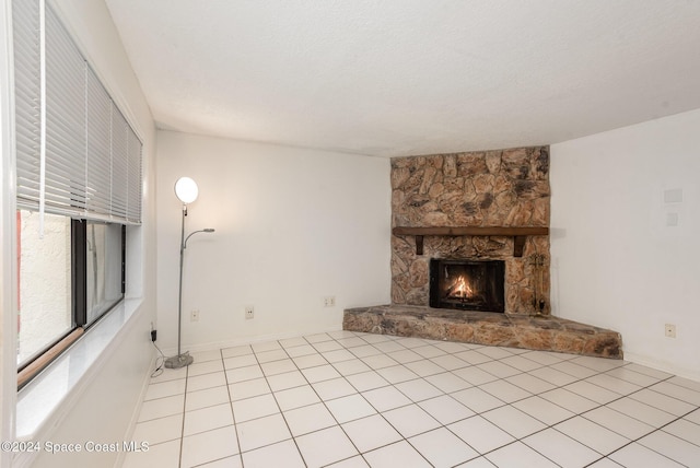 unfurnished living room featuring a fireplace, light tile patterned floors, and a textured ceiling