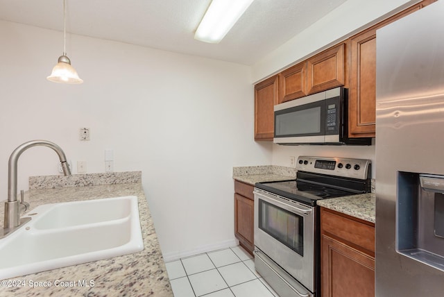 kitchen with decorative light fixtures, light stone countertops, sink, and appliances with stainless steel finishes