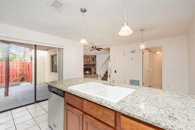 kitchen with sink, hanging light fixtures, stainless steel dishwasher, ceiling fan, and a fireplace