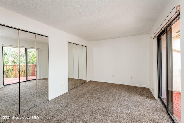 unfurnished bedroom with access to outside, multiple closets, carpet flooring, and a textured ceiling