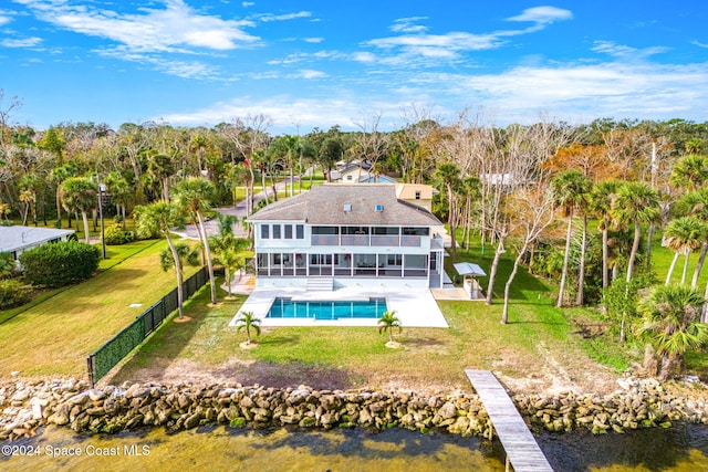 rear view of house featuring a fenced in pool, a patio area, a lawn, and a sunroom