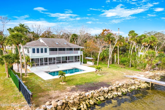 rear view of property featuring a sunroom, a fenced in pool, a water view, a patio area, and a yard