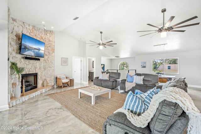 living room with ceiling fan, lofted ceiling, and a stone fireplace