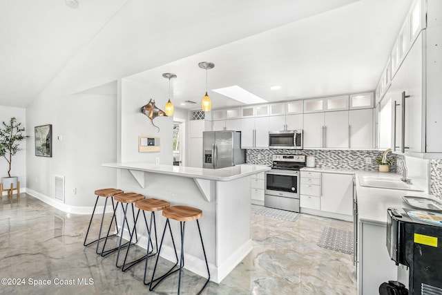 kitchen with white cabinets, appliances with stainless steel finishes, decorative backsplash, sink, and hanging light fixtures