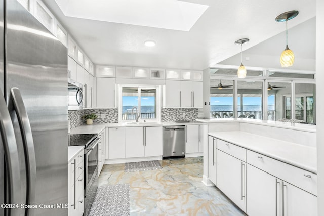 kitchen featuring decorative light fixtures, backsplash, white cabinetry, and stainless steel appliances