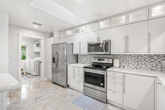 kitchen featuring white cabinets, backsplash, appliances with stainless steel finishes, and independent washer and dryer