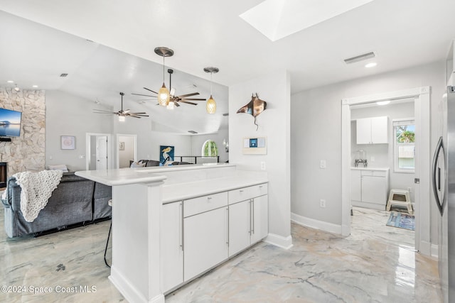 kitchen with a kitchen bar, hanging light fixtures, vaulted ceiling with skylight, white cabinets, and kitchen peninsula