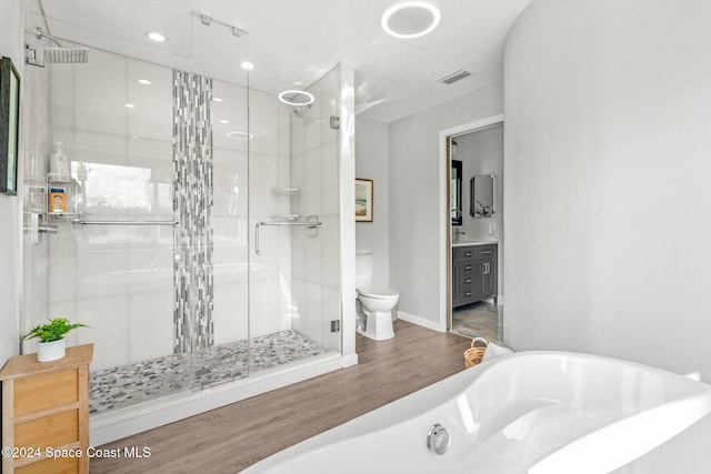 full bathroom with a textured ceiling, wood-type flooring, vanity, toilet, and separate shower and tub