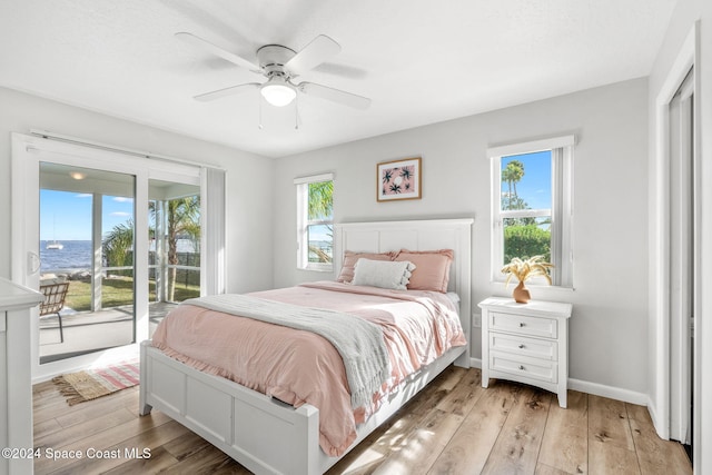 bedroom with ceiling fan, access to exterior, multiple windows, and light wood-type flooring