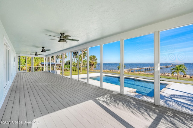 view of swimming pool featuring ceiling fan and a deck with water view