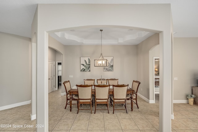 dining area with a notable chandelier, light tile patterned floors, and a tray ceiling