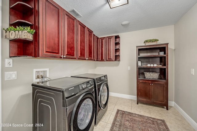 washroom with cabinets, washing machine and dryer, light tile patterned floors, and a textured ceiling