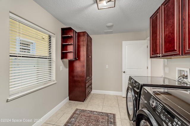 laundry room featuring washing machine and dryer, light tile patterned flooring, cabinets, and a textured ceiling