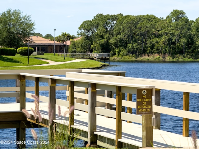 dock area with a lawn and a water view