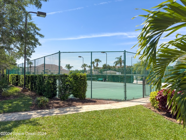 view of tennis court with a yard