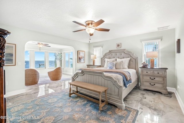100 Bonita St, Titusville, FL 32780 - bedroom with light marble finish floors, arched walkways, a ceiling fan, a water view, and a textured ceiling