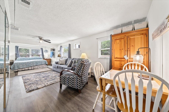 bedroom with multiple windows, ceiling fan, dark hardwood / wood-style flooring, and a textured ceiling